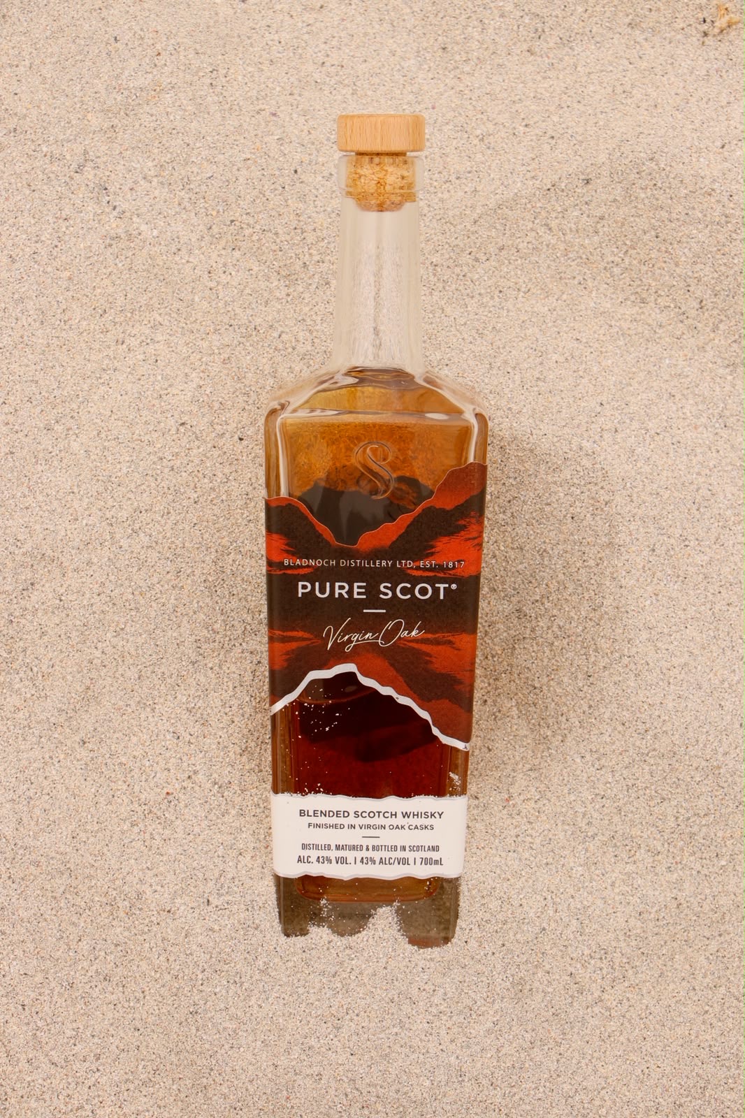 Pure Scot Virgin Oak bottle laid flat on clean beach sand
